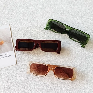 Detailed view of square sunglasses frames in dark green, dark red, and champagne tones