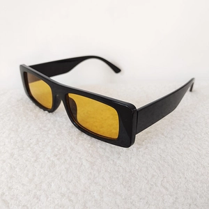 Detail of vintage rectangular sunglasses with glossy black frames and bright yellow lenses