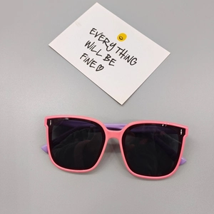 Detail view of pink and purple children's sunglasses with polarized lenses on a grey background
