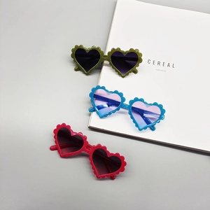 Close-up of heart-shaped kids sunglasses with glitter frames and wavy floral edges