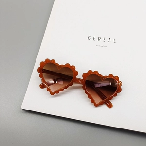 Detail view of heart-shaped kids sunglasses with brown glitter resin and wavy edges