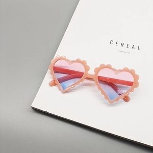 Close-up of pink glitter heart sunglasses for kids with gradient lenses on a magazine