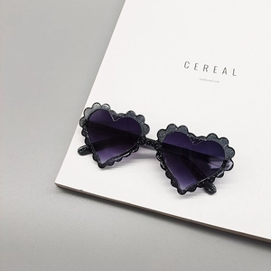 Detail of heart-shaped glitter sunglasses with scalloped edges and gradient purple lenses
