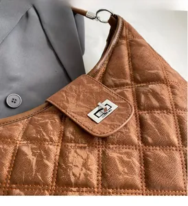 Detail of brown quilted faux leather bag with vintage texture and silver turn-lock clasp