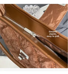 Close-up of smooth silver zipper and quilted texture on the brown PU shoulder bag