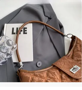Detail of brown quilted faux leather shoulder bag with classic diamond stitch and silver clasp