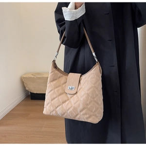 Detail of beige quilted shoulder bag with marble texture and vintage metal turn-lock