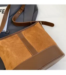 Detail of a brown two-tone shoulder bag featuring suede and smooth leather patchwork texture