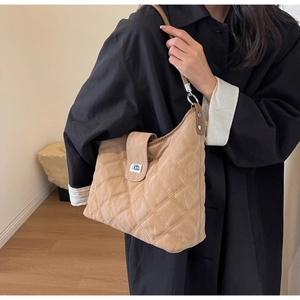Quilted beige hobo shoulder bag with silver clasp shown on person over a black coat