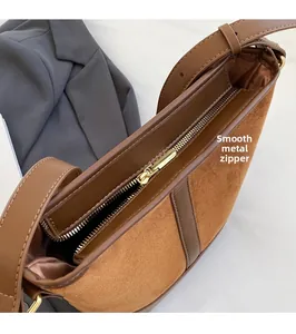 Detail of smooth gold zipper and contrast leather textures on brown bucket bag