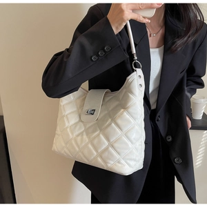 Detail of white quilted leather texture with metallic silver twist lock on shoulder bag