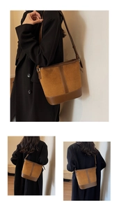 Detail of caramel brown suede bucket bag with leather trim and gold metal buckle