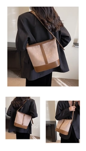 Detail view of large beige suede bucket bag with brown leather trim and shoulder strap