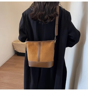 Close-up of vintage brown suede and leather patchwork bucket bag worn on shoulder