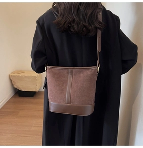 Detailed view of vintage brown suede bucket bag with leather trim on model