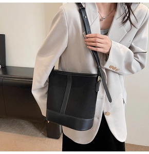 Detail of matte suede and smooth leather stitching on a black bucket shoulder bag