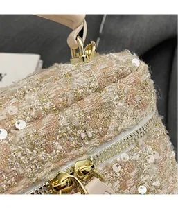 Detail of pink tweed fabric with sequins and gold double zippers on luxury mini bag