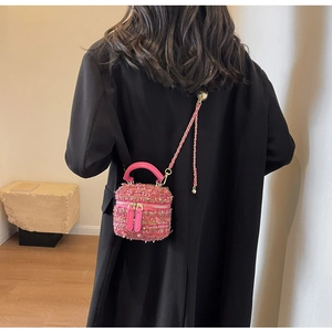 Detail einer Mini-Tasche aus Tweed in Fuchsia mit Goldkette über schwarzem Blazer