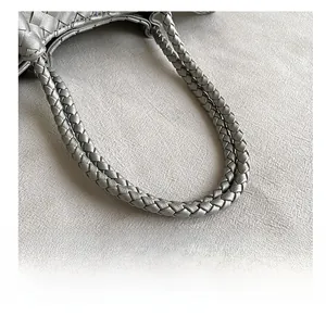 Detailed close-up of woven silver leather straps and luxury texture of the handbag