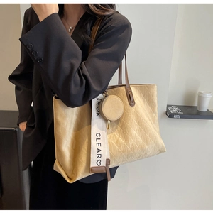 Detail of quilted suede tote bag with wide logo strap and round coin purse attachment