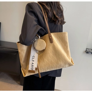 Detail of beige quilted tote bag with wide CLEAR letter strap and round pouch
