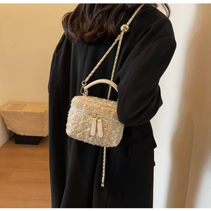 Détail du sac bandoulière en tweed avec chaîne dorée et paillettes sur manteau noir chic