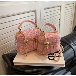 Pink tweed crossbody box bags in two sizes with gold chain straps on white decorative books