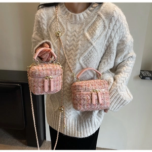 Detailaufnahme der rosa Tweed-Textur und verstellbaren Goldkette an der Mini-Beuteltasche