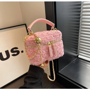 Detailaufnahme der rosa Tweed-Minitasche mit Goldkette und floraler Metallkugel-Deko