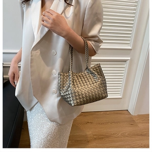 Close-up of woven metallic gold tote bag paired with white blazer and sequin skirt