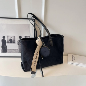 Close-up of black quilted tote bag featuring a decorative logo strap and mini coin purse