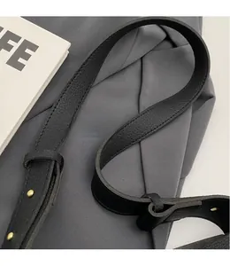 Détail de la bandoulière en cuir noir grainé avec des boucles métalliques dorées