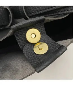 Détail du fermoir magnétique doré sur le sac seau en cuir noir à grain de litchi