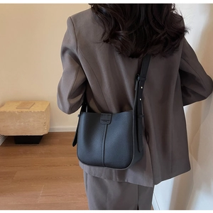Détail du sac seau en cuir grainé noir avec boucle et bandoulière réglable sur un mannequin