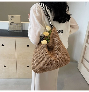Détail d'un grand sac bandoulière en paille avec bandoulière rayée tissée