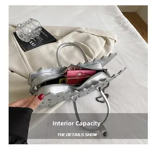 Detail view showing large capacity of the silver dinosaur bag with wallet and lipstick