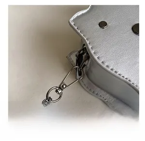 Detailed macro view of high-quality gunmetal hook and chain on silver lychee leather bag
