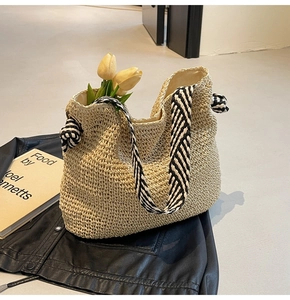 Detail van strooien tas met zwart-wit gestreept geknoopt handvat en bloemen