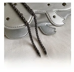 Close-up of metallic silver dinosaur bag with black rivets and dark gunmetal chain strap