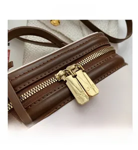 Close-up of golden dual zippers and stitching on white and brown leather bag