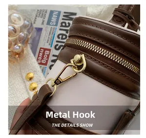 Detailed close-up of the golden hardware hooks and zipper on this bicolor bucket handbag