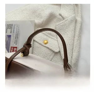 Top detail of brown and white bucket bag with gold zippers and leather handle