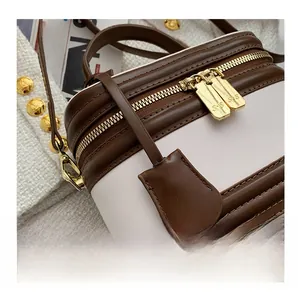Detailed macro of a two-tone bucket bag with gold zipper and decorative leather tag
