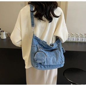 Detail of blue denim tote bag showing adjustable strap and small round coin purse attachment