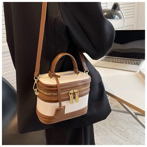 Close-up of dual-tone beige and brown handbag with gold zipper and stylish handle