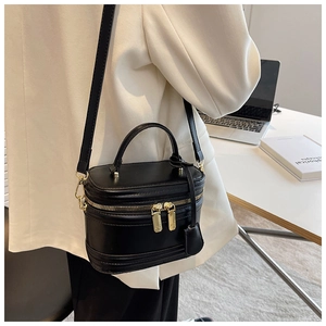 Chic black vanity case bag with gold hardware worn by a model in an office setting