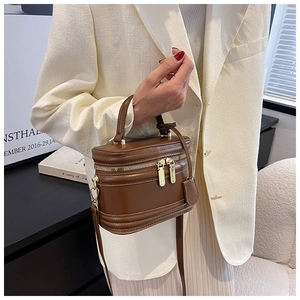 Close-up of vintage dark brown leather bucket bag with dual gold zippers and smooth texture