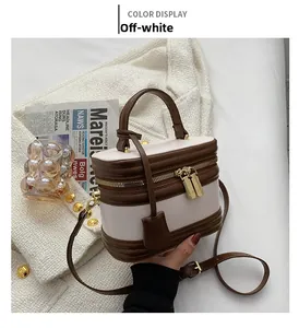 Close-up of cream white retro crossbody bag with dual-zipper and top handle