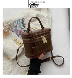 Close-up of brown cylindrical bucket bag with gold hardware on white textured coat