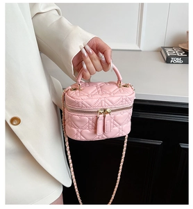 Close-up of pink heart-quilted mini box bag with gold chain strap held by a model